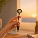 Una mano sosteniendo la compacta lámpara Lumé con luz de atardecer de fondo